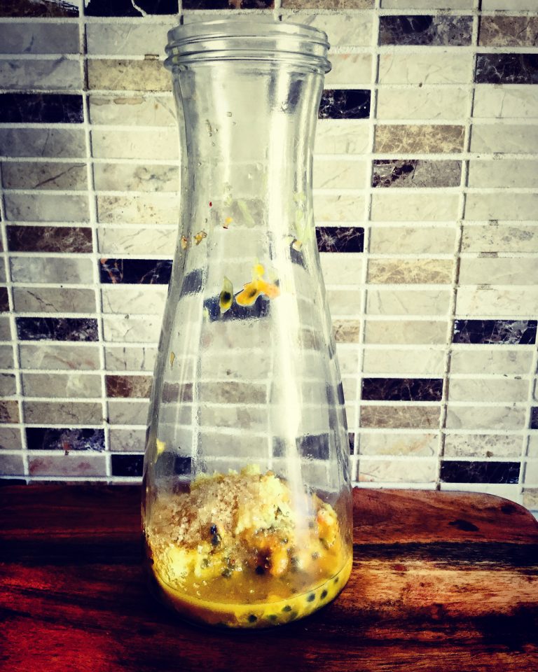 Passion fruit pulp, grated ginger and sugar in the bottom of a glass bottle