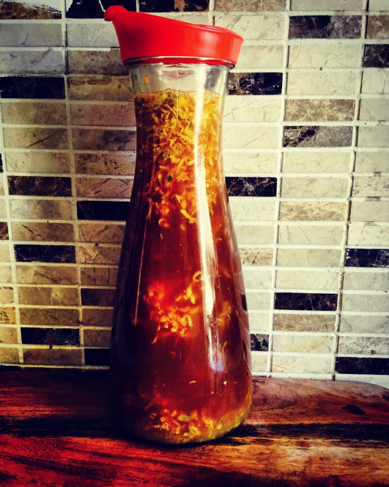 A bottle of kombucha with passion fruit and grated ginger, closed with a red lid