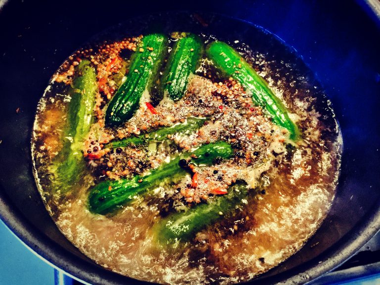 Small cucumbers simmering in spiced vinegar brine