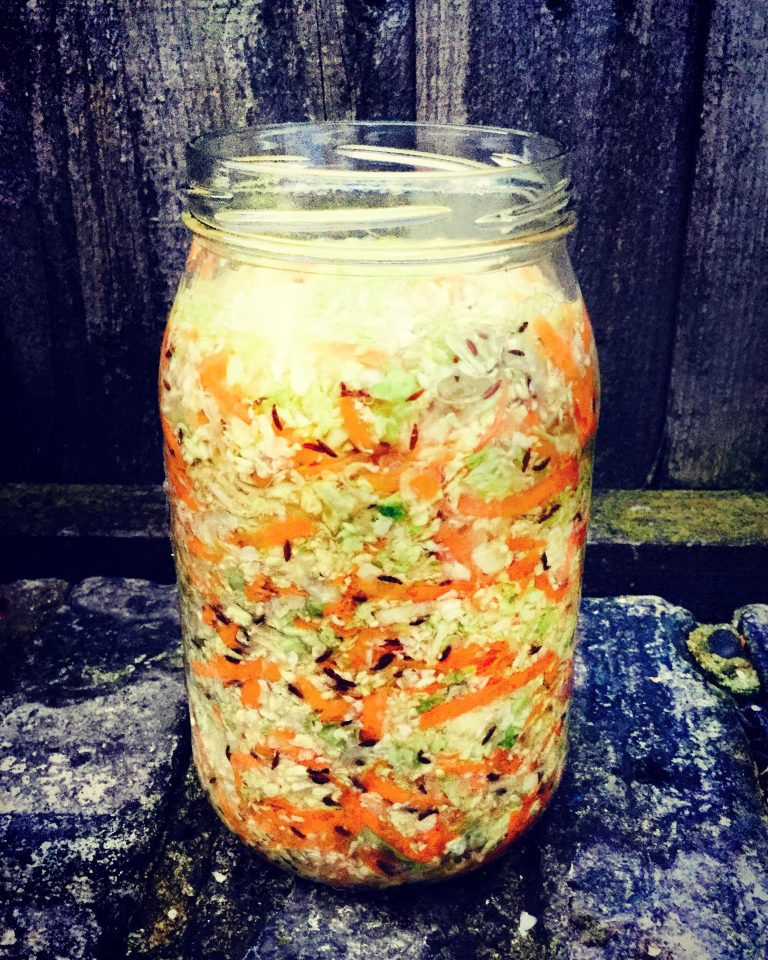 A jar packed with shredded cabbage, carrot and caraway