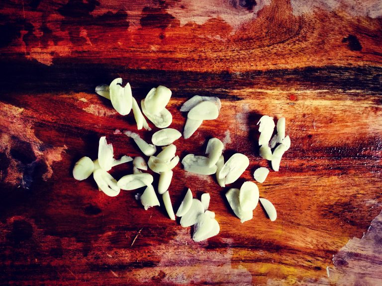 Thinly sliced garlic on a wooden board