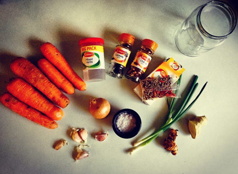 Ingredients for fermented carrots: whole carrots, onion, spring onions, garlic, ginger, turmeric, sea salt, dried herbs and spices, and an empty glass jar