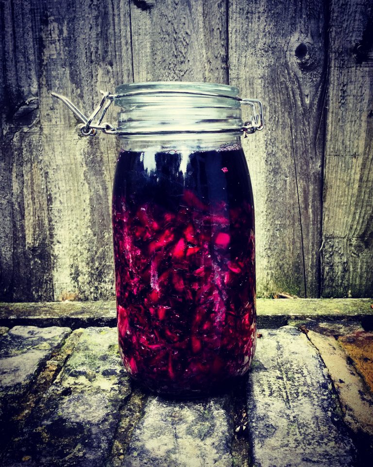 A clip-top jar of deep purple red cabbage and beetroot sauerkraut