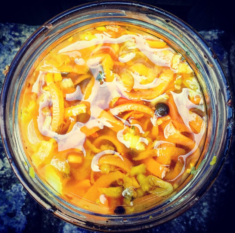 Top view into a jar of fermenting carrots with a thin white film on the surface of the brine