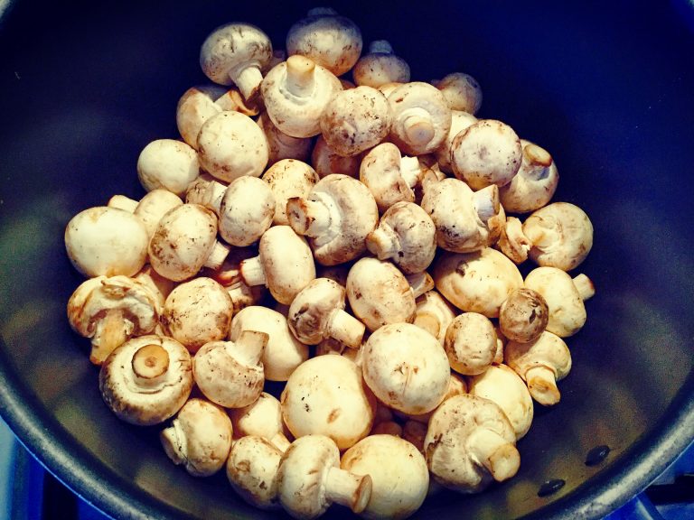 Whole button mushrooms in a pan before cooking
