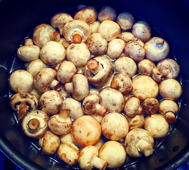 Button mushrooms simmering in water in a pan
