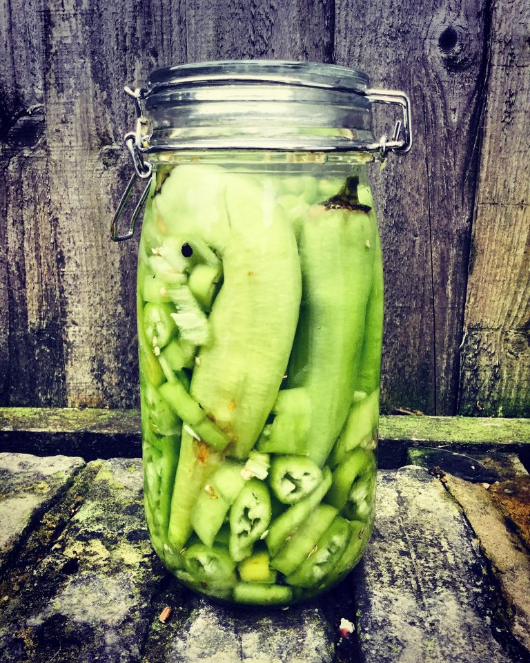 A clip-top jar of banana peppers covered in brine