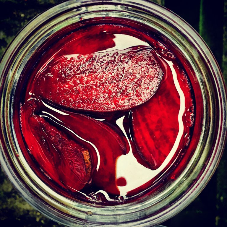 Top view of beet slices under red brine in a jar