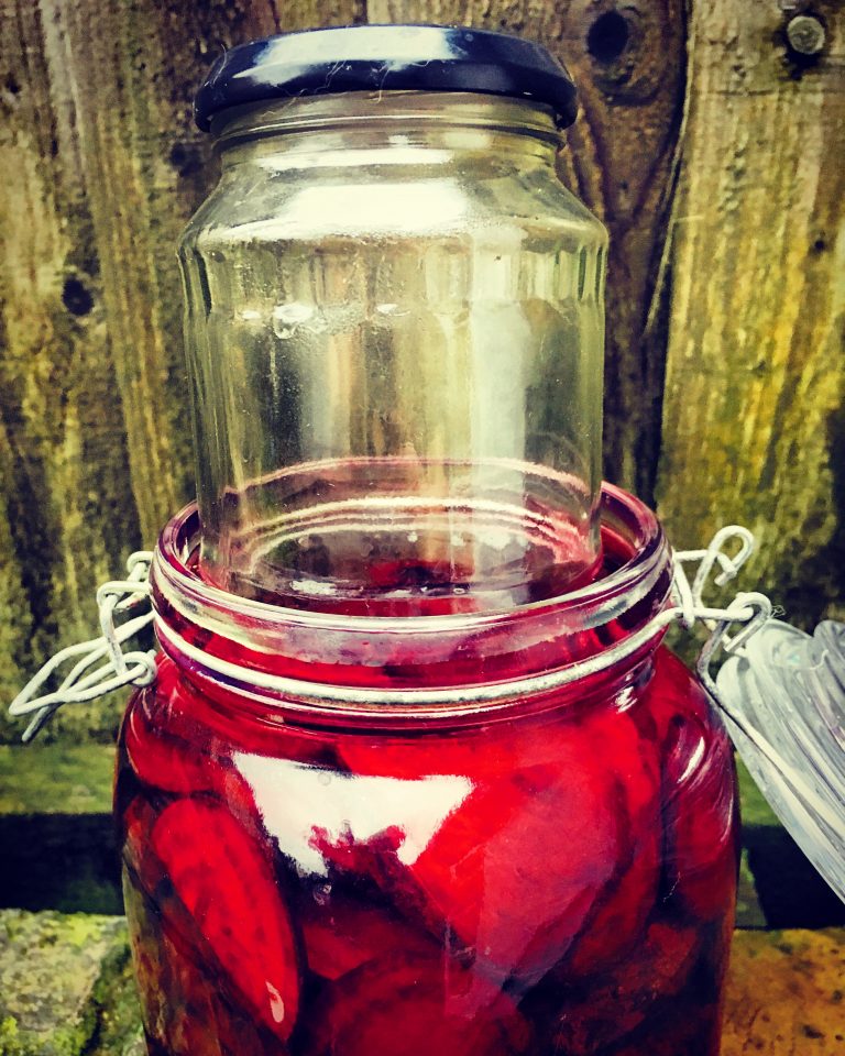 A small glass jar pressed into the mouth of the beet jar as a weight