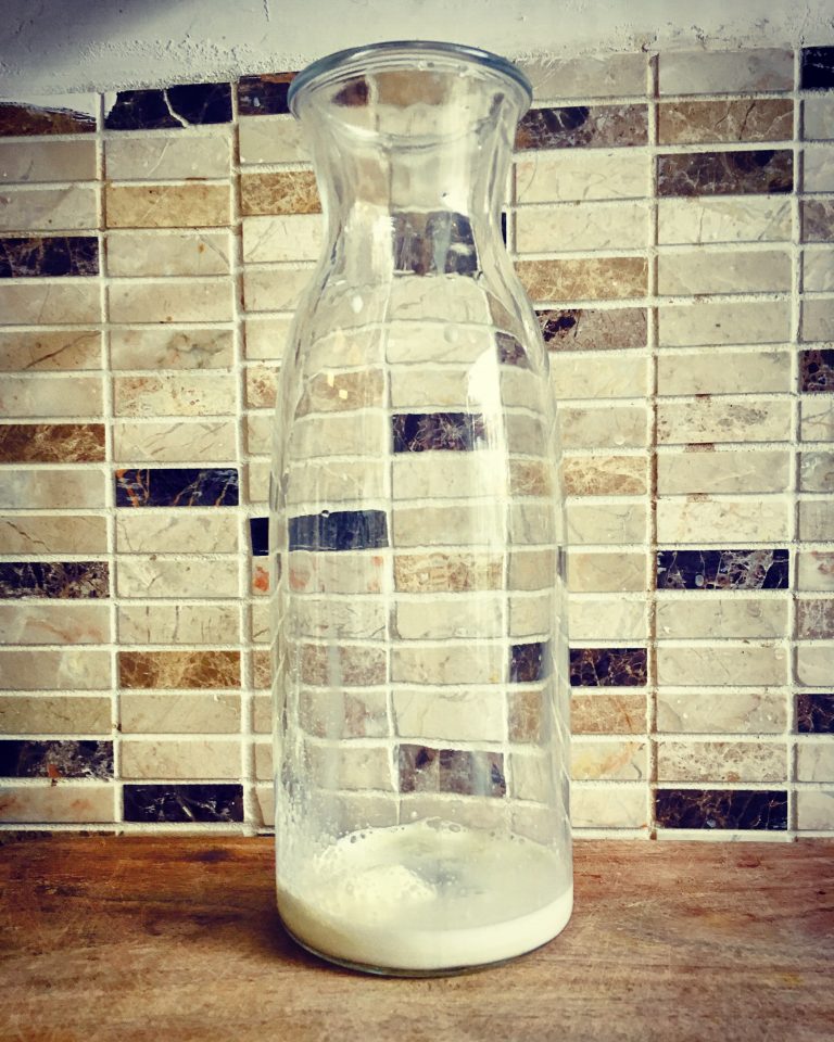 A glass bottle with the kefir starter mixed into a splash of milk at the bottom