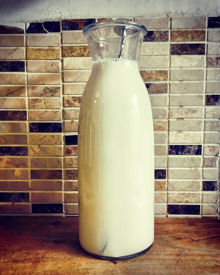 A glass bottle filled with milk and kefir culture before fermenting